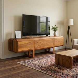 Puede incluir: Sal&oacute;n moderno con un mueble de TV de madera grande con tres cajones, un televisor de pantalla plana y una alfombra estampada. Un sill&oacute;n beige y una mesa de centro de madera completan el espacio. La habitaci&oacute;n est&aacute; iluminada.