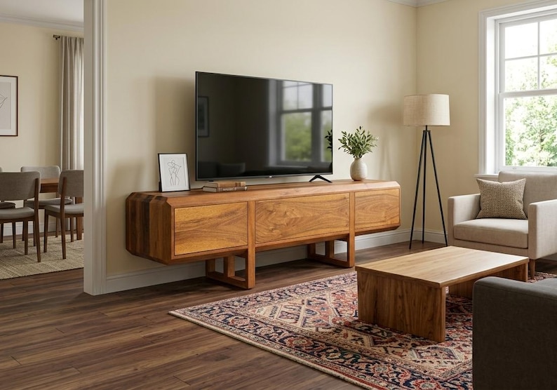 Puede incluir: Sal&oacute;n moderno con un mueble de TV de madera grande con tres cajones, un televisor de pantalla plana y una alfombra estampada. Un sill&oacute;n beige y una mesa de centro de madera completan el espacio. La habitaci&oacute;n est&aacute; iluminada.