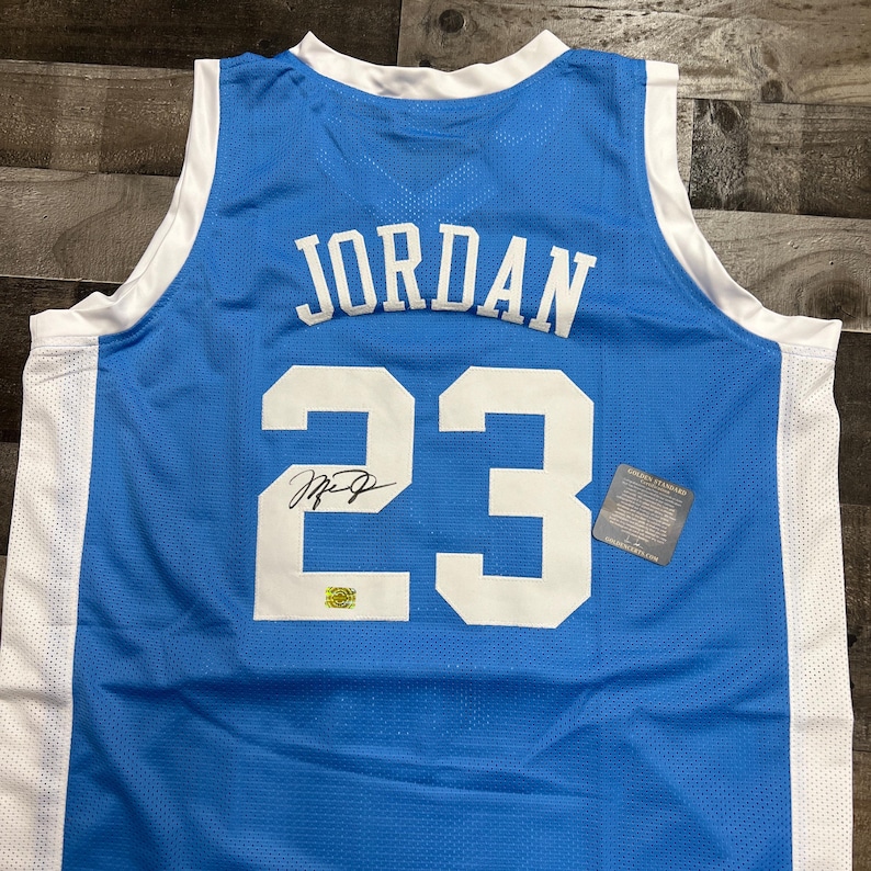 K&ouml;nnte beinhalten: Hellblaues Basketballtrikot mit wei&szlig;em Besatz, mit dem Namen "JORDAN" und der Nummer "23" in Wei&szlig;. Enth&auml;lt ein Autogramm und ein Etikett. Das Trikot besteht aus atmungsaktivem Mesh-Material.