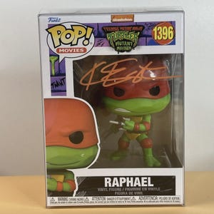 May include: A Funko Pop! Movies figure of Raphael from Teenage Mutant Ninja Turtles: Mutant Mayhem. The figure is green with a red mask and holds two sai. The box has the Funko Pop! and Nickelodeon logos, and the figure is signed.
