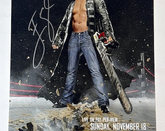 May include: A promotional poster for WWE Survivor Series featuring a blonde wrestler in a black leather coat and blue jeans holding a chainsaw. The poster includes an autograph, the text Survivor Series, and event details for Sunday, November 18.