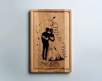 May include: Wooden rectangular cutting board with a carved border. The board features a black silhouette of a couple embracing, with the words "Mr & Mrs" in elegant script. Decorative vines frame the couple, creating a wedding theme.