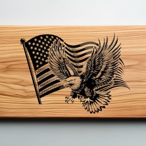 May include: Wooden cutting board with a laser-etched design featuring the American flag and a bald eagle. The eagle is depicted with outstretched wings, and the flag is waving in the background. The board has a natural wood grain.
