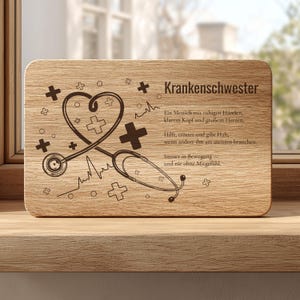 Könnte beinhalten: Ein rechteckiges Holzschild mit einer dunkelbraunen Lasergravur, die ein herzförmiges Stethoskop, medizinische Kreuze und den Text zeigt: Krankenschwester, Ein Mensch mit ruhigen Händen, klarem Kopf und großem Herzen, Hilft, tröstet und gibt Halt, wenn andere ihm am meisten brauchen, Immer in Bewegung – und nie ohne Mitgefühl.