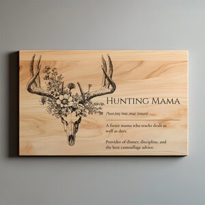 K&ouml;nnte beinhalten: Holzschild mit dem Text "HUNTING MAMA" und einem Hirschsch&auml;del mit floralen Akzenten. Das Schild enth&auml;lt eine Definition von "Hunting Mama" und ist ein dekorativer Artikel.