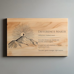 May include: Wooden plaque with the words "DIFFERENCE MAKER" and a definition. The design includes a mountain scene with a figure at the summit and sun rays. The text also includes "game changer, light bearer."
