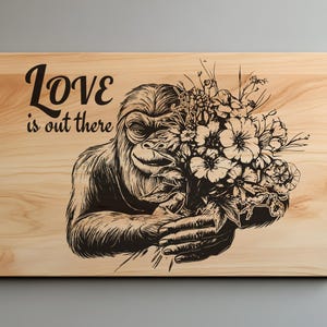 May include: Wooden sign with a black illustration of an ape holding a bouquet of flowers. The text "Love is out there" is above the ape. The sign is made of light-colored wood.