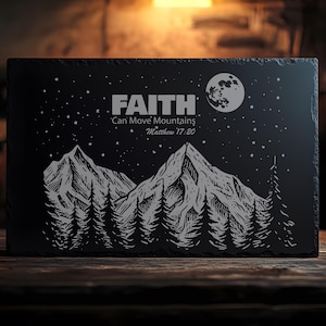 May include: Black slate plaque with a white design of mountains, trees, and a moon. The text "FAITH Can Move Mountains Matthew 17:20" is written in white.