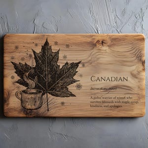 Könnte beinhalten: Holzschneidebrett mit einer Ahornblatt- und einer Kaffeetassen-Illustration. Das Wort "CANADIAN" ist auf dem Brett aufgedruckt, zusammen mit einer Definition. Das Brett hat eine natürliche Holzmaserung.