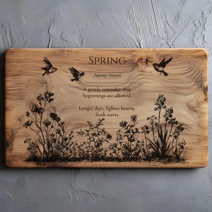 May include: Wooden rectangular serving board with the word "SPRING" and the definition. The board features etched images of birds and floral designs. The text reads, "A gentle reminder that beginnings are allowed. Longer days, lighter hearts, fresh starts."