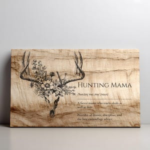 K&ouml;nnte beinhalten: Holzschild mit dem Text "HUNTING MAMA" und einem Hirschsch&auml;del mit floralen Akzenten. Das Schild enth&auml;lt eine Definition von "Hunting Mama" und ist auf einem hellbraunen Holzmaserungshintergrund gedruckt.