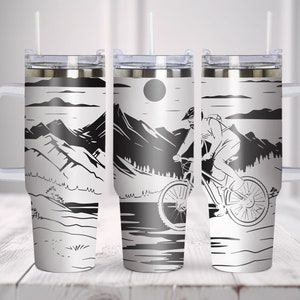 Op de afbeelding: Drie reistassen van roestvrij staal met een zwart-wit mountainbike-ontwerp. De bekers hebben een handvat en een deksel met een rietje.