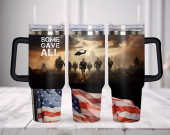 May include: A stainless steel tumbler with a handle, clear lid, and straw. The design features a military scene with soldiers walking toward a helicopter at sunset, the text "SOME GAVE ALL," and a waving American flag at the base of the cup.
