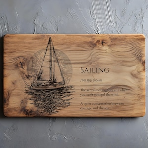 May include: Wooden cutting board with a sailboat illustration and the word "SAILING" in black text. The definition of sailing is also included. The board has a rectangular shape and a natural wood grain.