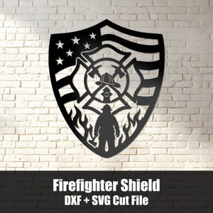 May include: A black metal wall art piece shaped like a shield featuring a cutout design of an American flag, a firefighter helmet, crossed axes, a fire hydrant, and a firefighter silhouette standing amidst flames with the text Firefighter Shield DXF + SVG Cut File.
