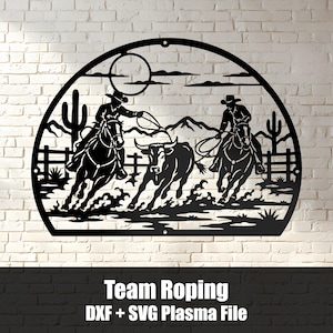 Pode incluir: Uma peça de arte de parede em metal preto com uma silhueta semicircular de dois cowboys a cavalo laçando um boi numa paisagem desértica com catos, montanhas e um sol. O texto "Team Roping DXF + SVG Plasma File" está impresso abaixo.