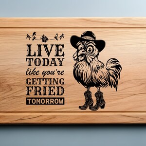 May include: A wooden cutting board with a black and white illustration of a rooster wearing a cowboy hat and boots. The text "LIVE TODAY like you're GETTING FRIED TOMORROW" is engraved on the board.