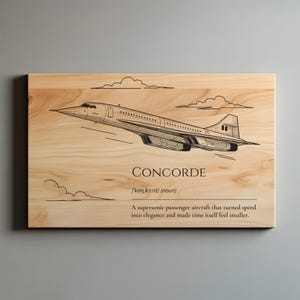 May include: Wooden wall art featuring a black and white illustration of the Concorde supersonic passenger aircraft. The word "CONCORDE" is above a definition. The artwork is on a light-colored wood grain background.