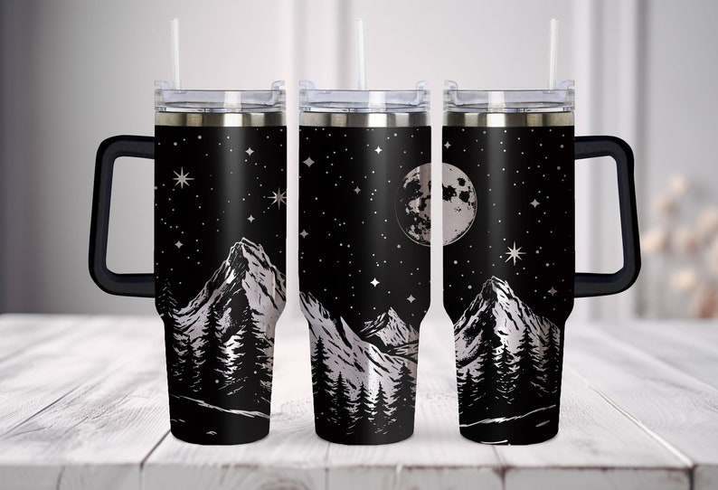 May include: Three stainless steel travel mugs with black handles and lids. The mugs feature a black and white design of mountains, a full moon, and stars against a black background.