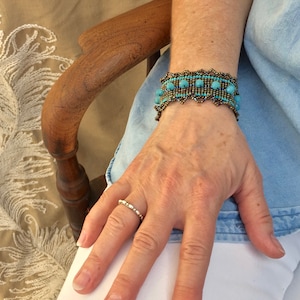 May include: A turquoise and brown beaded bracelet with a scalloped edge. The bracelet is worn on a person's wrist.
