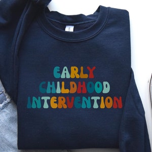 May include: A navy blue sweatshirt with the text "EARLY CHILDHOOD INTERVENTION" in rainbow colored letters.