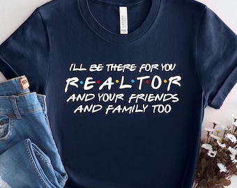 May include: Navy blue t-shirt with the text "I'll be there for you Realtor and your friends and family too" in white. The word "Realtor" is in the style of the TV show Friends. The shirt is paired with blue jeans.