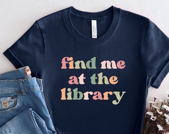 May include: A navy blue t-shirt with the text "find me at the library" in rainbow colors.