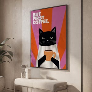 Peut inclure: Une affiche encadrée représentant un chat noir tenant une tasse de café orange. Le chat porte une chemise rayée sur un fond de rayures orange et roses. Le texte "BUT FIRST COFFEE" est affiché en haut de l'affiche.