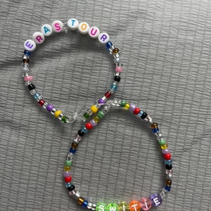 May include: Two colorful beaded necklaces with letter beads spelling out "ERA TOUR" and "SWITIE".