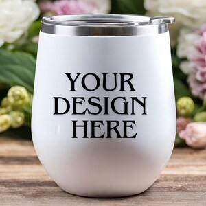 Peut inclure: Un gobelet &agrave; vin en acier inoxydable blanc avec un couvercle argent&eacute;. Le gobelet porte l'inscription "YOUR DESIGN HERE" imprim&eacute;e sur le devant.