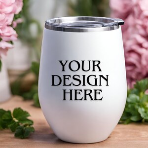 Peut inclure: Un gobelet isotherme en acier inoxydable blanc avec un couvercle. Le gobelet porte l'inscription "YOUR DESIGN HERE" imprim&eacute;e sur le c&ocirc;t&eacute;.