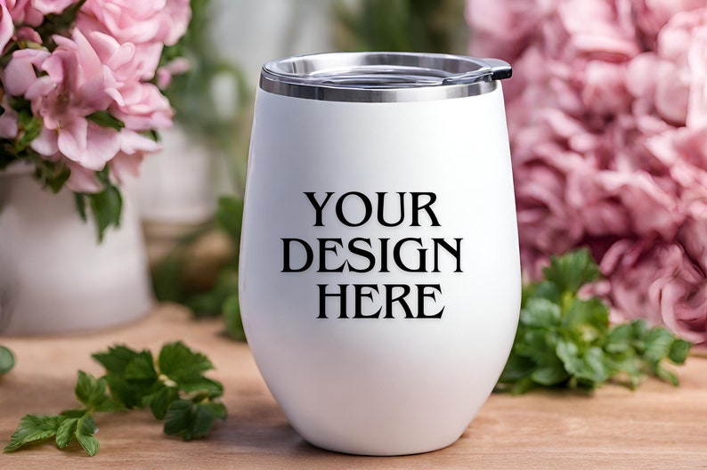 Peut inclure: Un gobelet isotherme en acier inoxydable blanc avec un couvercle. Le gobelet porte l'inscription "YOUR DESIGN HERE" imprim&eacute;e sur le c&ocirc;t&eacute;.