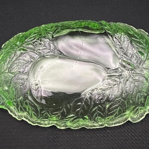 May include: A green glass serving dish with a pear design. The dish has a leaf pattern around the pears and handles on each side. The dish is approximately 10 inches long and 6 inches wide.