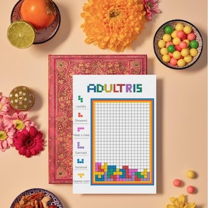Peut inclure: Un pense-bête Adultris blanc avec une grille et des blocs colorés de style Tetris en bas. La liste de contrôle comprend des invites telles que « Lessive » et « Exercice ». L'image présente également un journal rose, des fruits, des fleurs et des collations.