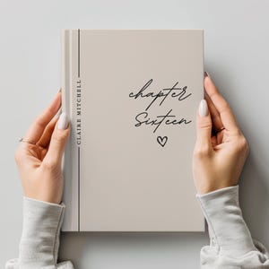 May include: A light beige hardcover book featuring the text "chapter Sixteen" in a black cursive font, a small heart icon, and the name "CLAIRE MITCHELL" printed vertically in a black sans-serif font along a thin black line on the left side.