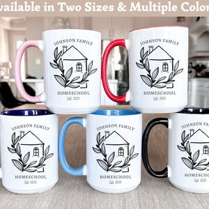 May include: White ceramic mugs with colored handles and interior rims. Each mug features a black illustration of a house with the text "JOHNSON FAMILY HOMESCHOOL Est. 2025". Handle colors include pink, red, blue, light blue, and black.