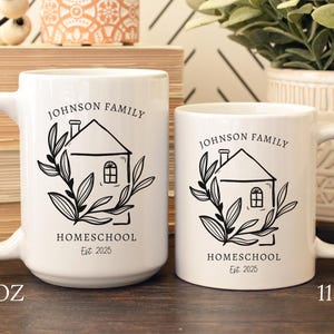 May include: Two white ceramic mugs with black text and graphics. The mugs have a house design with the words "JOHNSON FAMILY HOMESCHOOL Est. 2025". The larger mug is 15 oz, and the smaller mug is 11 oz.