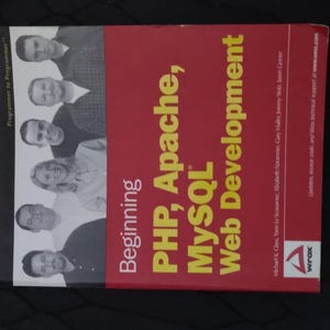 May include: A red book titled "Beginning PHP, Apache, MySQL Web Development" with a Wrox logo. The book cover features a group of people smiling and looking at the camera.