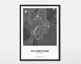 May include: A framed grayscale map print of the Silverstone race track in the United Kingdom. The print features the track layout, surrounding roads, and the text "SILVERSTONE" and coordinates. The print is in a black frame.