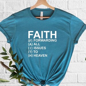 以下が含まれることがあります： 白文字で「FAITH」と書かれたターコイズブルーのTシャツ。文字は頭字語に分解されています。(F) Forwarding (A) All (I) Issues (T) To (H) Heaven.