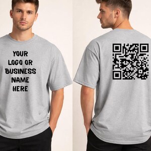 May include: A light gray t-shirt with the text "YOUR LOGO OR BUSINESS NAME HERE" on the front. The back of the shirt features a black QR code. The shirt is short-sleeved and made of a soft material.