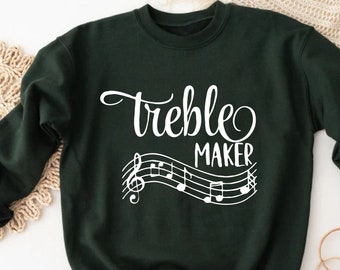May include: A dark green sweatshirt with white text that reads "Treble Maker" and a musical note design.