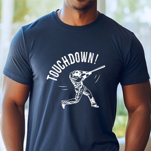 May include: A navy blue t-shirt with a white graphic of a baseball player swinging a bat and the text "TOUCHDOWN!"