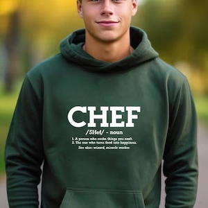 May include: A dark green hooded sweatshirt with the word "CHEF" in white lettering and a definition of the word below. The definition reads: "A person who cooks things you can't. The one who turns food into happiness. See also: wizard, miracle worker."