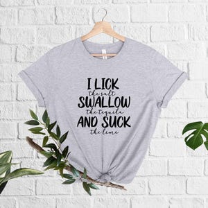 May include: A gray t-shirt with black text that reads "I lick the salt swallow the tequila and suck the lime".