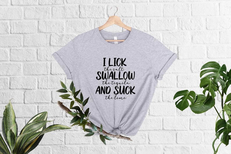May include: A gray t-shirt with black text that reads "I lick the salt swallow the tequila and suck the lime".