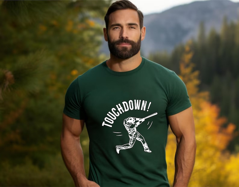 May include: A green t-shirt with a white graphic of a baseball player swinging a bat and the text "TOUCHDOWN!"