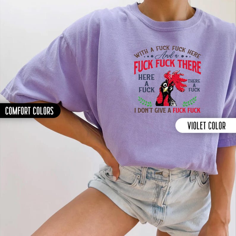 May include: A violet-colored t-shirt with the text "WITH A FUCK FUCK HERE And a FUCK FUCK THERE HERE A FUCK THERE A FUCK I DON'T GIVE A FUCK FUCK" and a rooster graphic. The shirt is labeled "COMFORT COLORS" and "VIOLET COLOR".