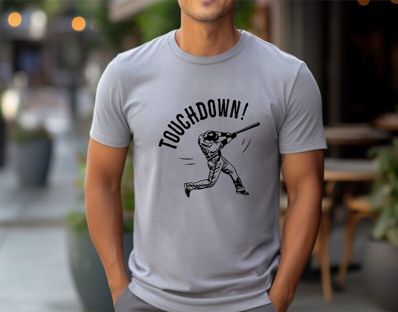 May include: A gray t-shirt with a black graphic of a baseball player swinging a bat. The text "TOUCHDOWN!" is printed above the player.