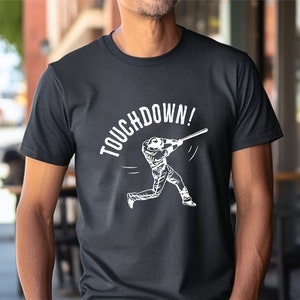 May include: Black t-shirt with a white graphic of a baseball player swinging a bat and the text "TOUCHDOWN!"